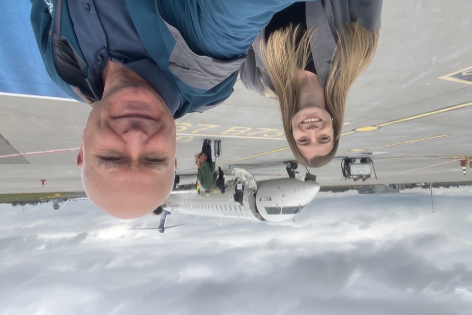 To kolleger tager en selfie udendørs ved lufthavnen